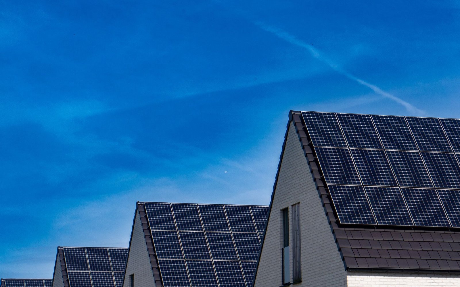 Modern houses fitted with rooftop solar panels against a clear blue sky
