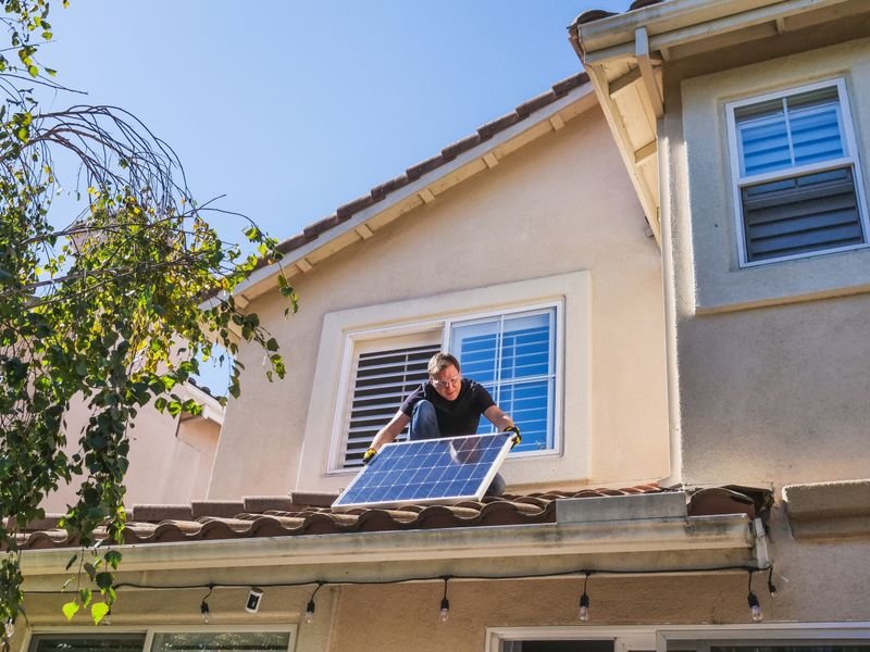 Engineer installing a solar panel on a residential roof
